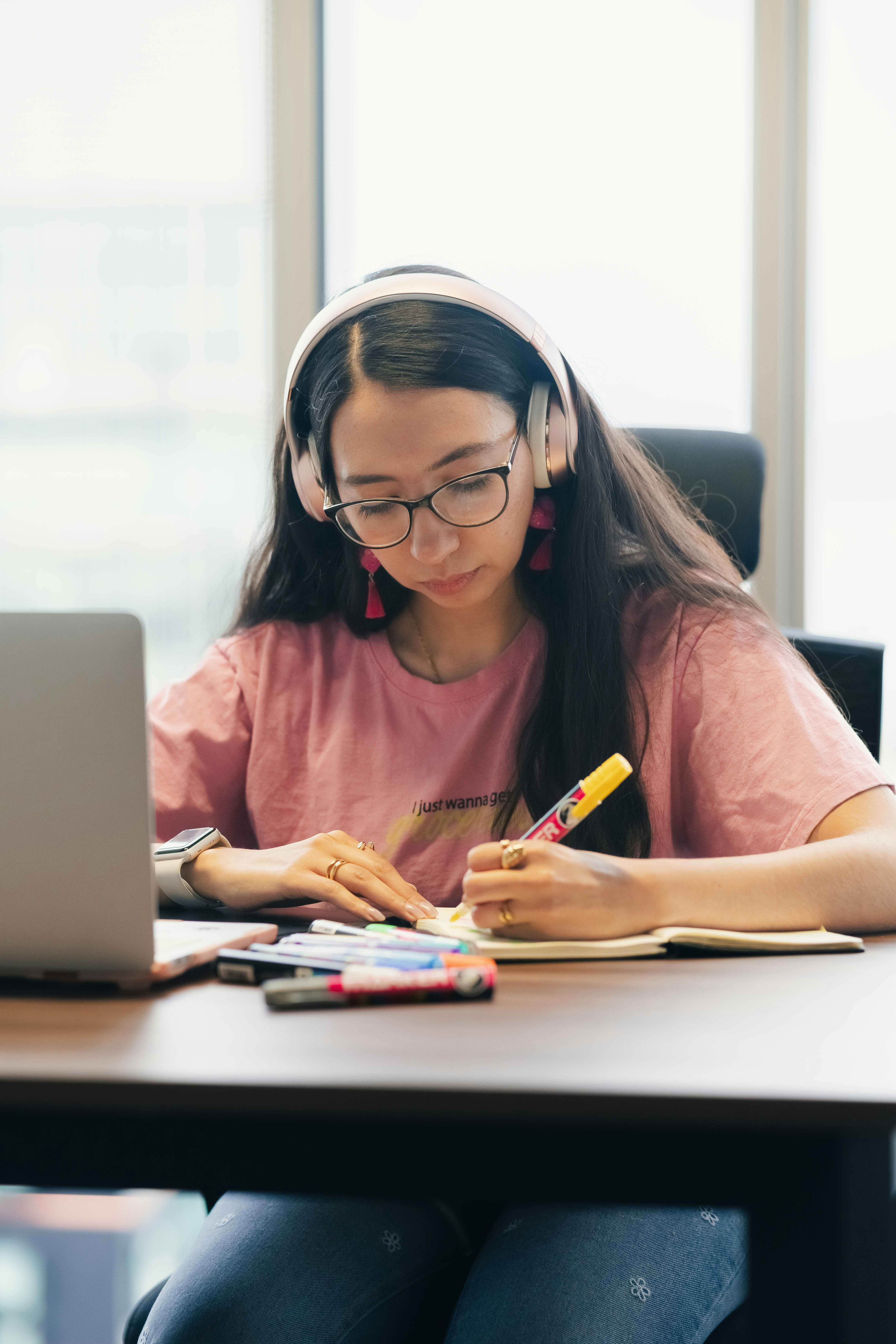 College student working at a desk with a laptop, notebook, and study tools